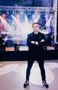 Piotr Wiater na tle sceny z oświetleniem estradowym przed imprezą firmową