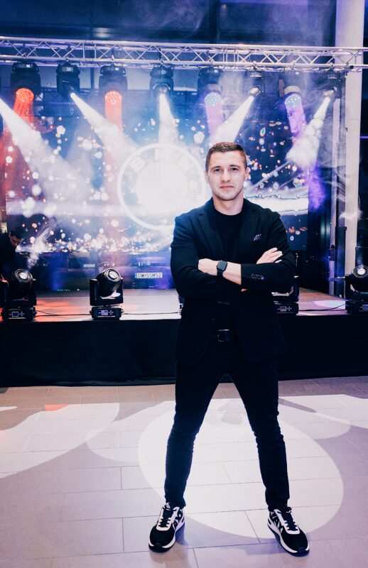 Piotr Wiater na tle sceny z oświetleniem estradowym przed imprezą firmową