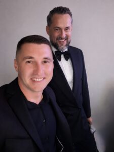 Piotr Wiater z wodzirejem w smokingach podczas eleganckiej gali