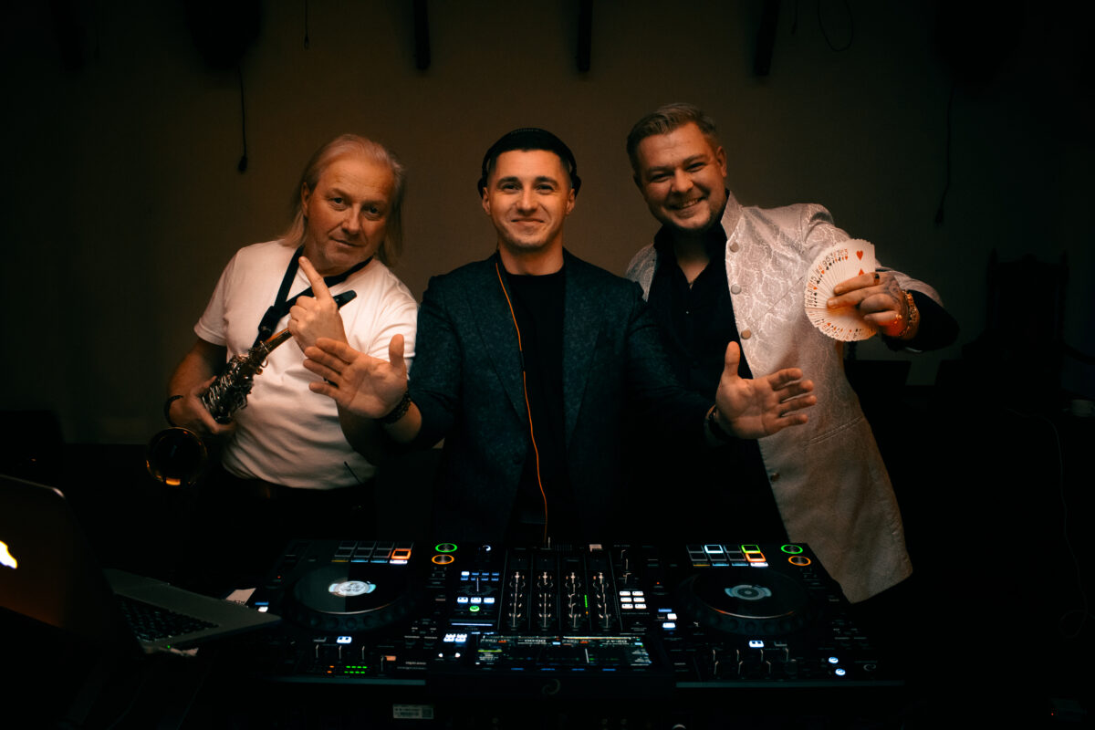 DJ Piotr Wiater z muzykami – saksofonistą i wokalistą – przy konsoli DJ-skiej