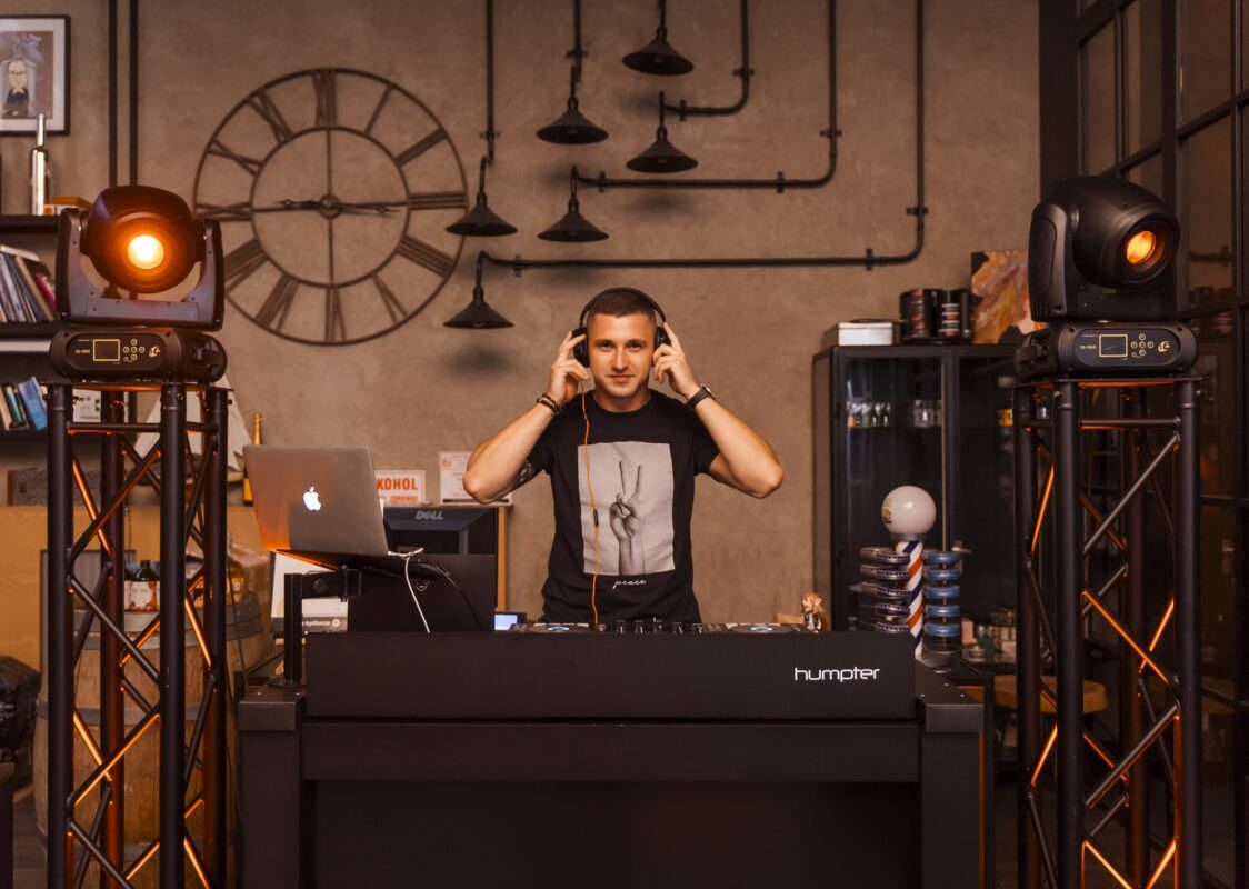 Piotr Wiater w słuchawkach za konsolą DJ-ską w industrialnym wnętrzu