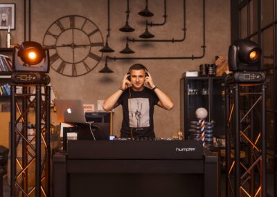 Piotr Wiater w słuchawkach za konsolą DJ-ską w industrialnym wnętrzu
